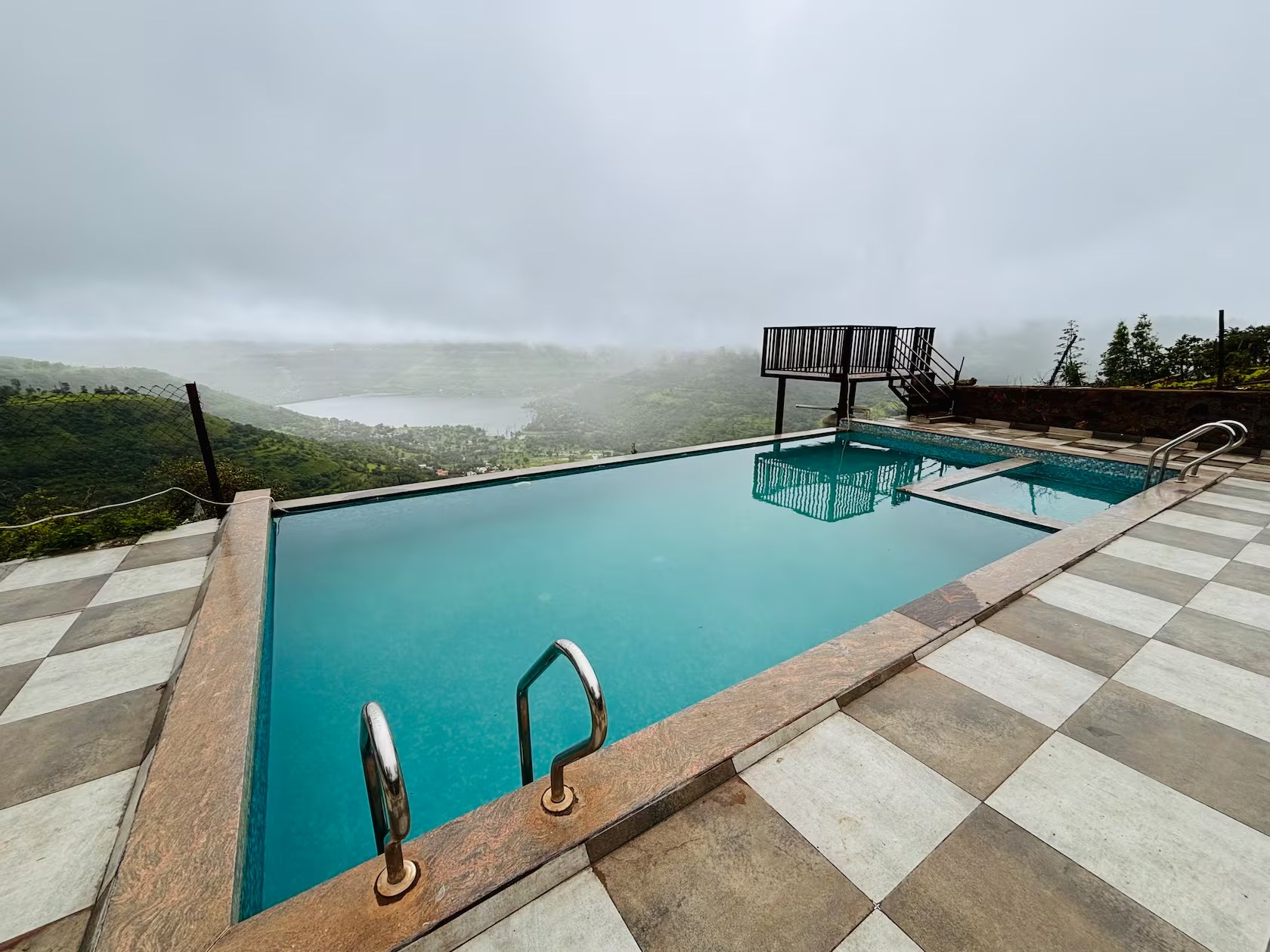 Infinity pool in monsoon mist with Mahu Dam view — Panchgani villa stay